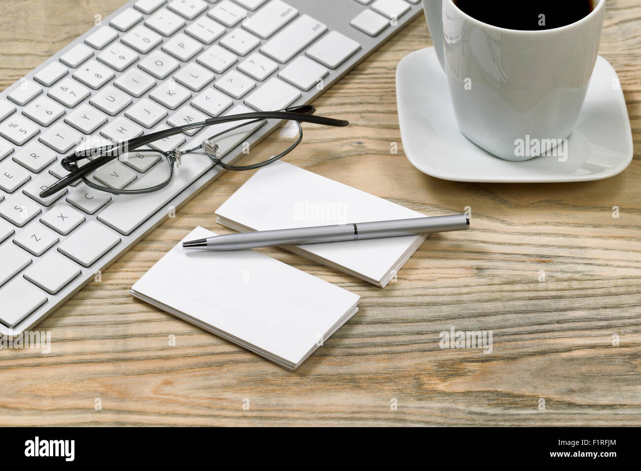 Close up de cartes d'affaires et l'argent stylo. Clavier d'ordinateur, lunettes de lecture et tasse de café en arrière-plan sur le bureau. Banque D'Images