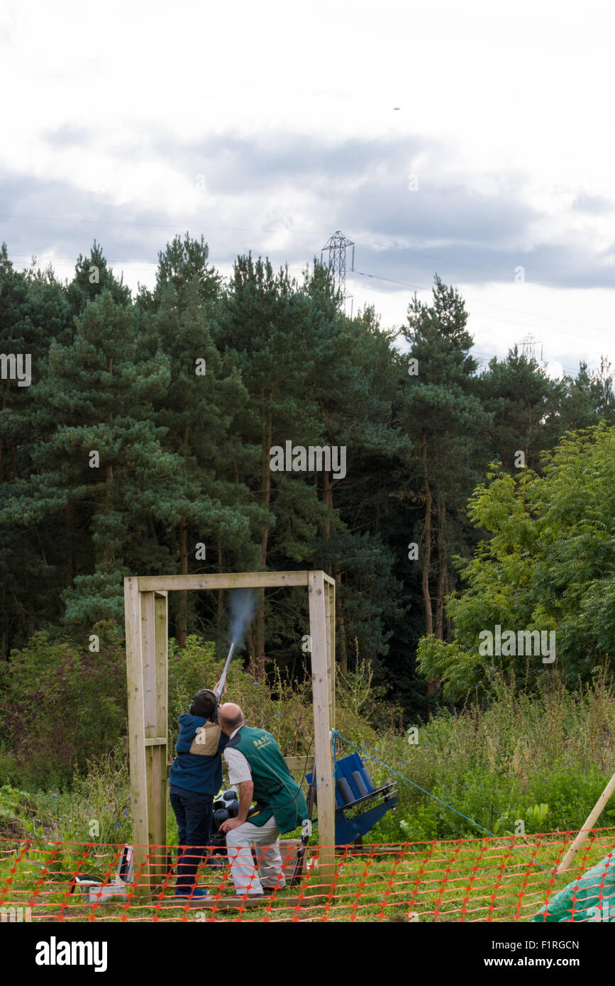 Un jeune garçon le tir au pigeon d'argile avec un fusil de chasse à l'Beckbury Shropshire UK Show 2015 Banque D'Images