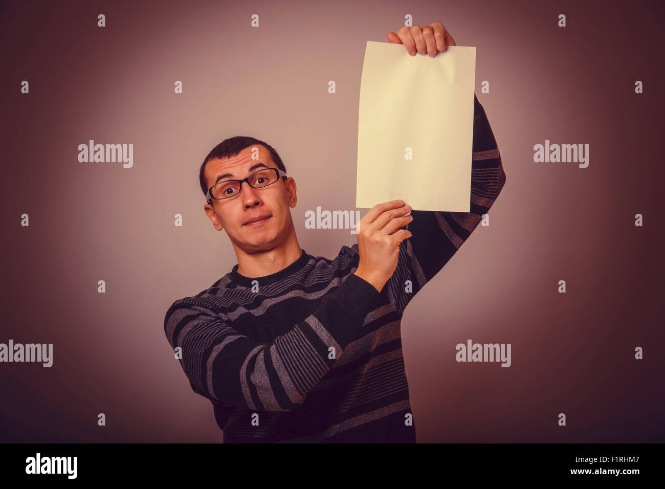 Homme européen tenant une feuille de papier blanc sur un fond gris b Banque D'Images