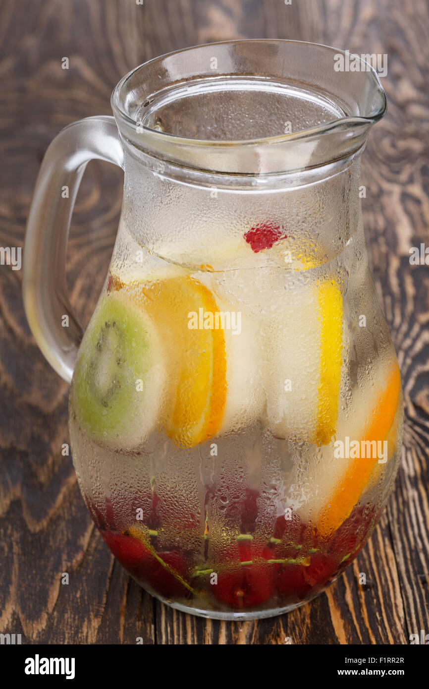 Pichet en verre de l'eau enrichie de cerises detox et surgelés en quartiers. Plein pot sous forme de brouillard d'eau froide avec popsicl Banque D'Images