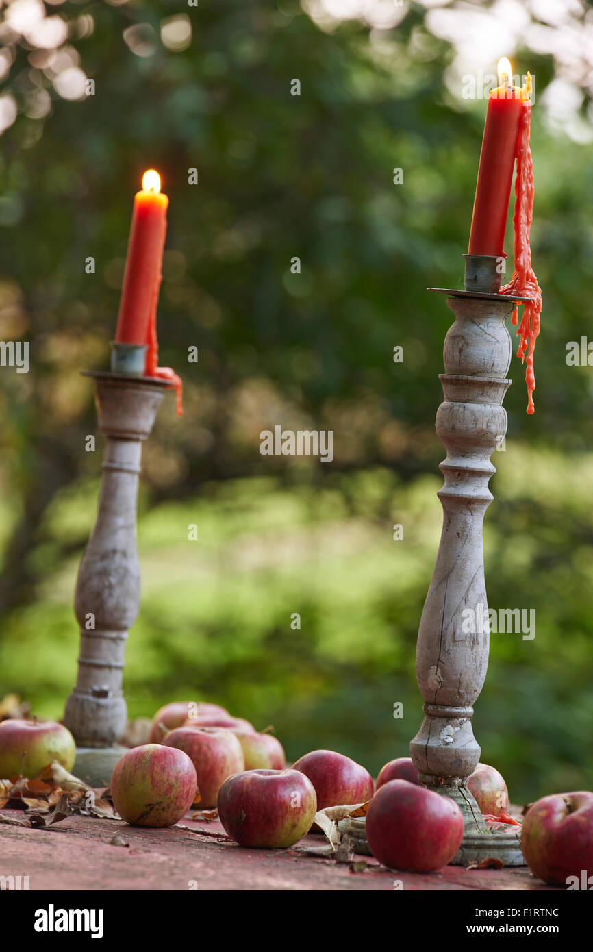 Un ensemble de bougies allumées au sommet d'une table de pique-nique de pommes dans un verger. Banque D'Images