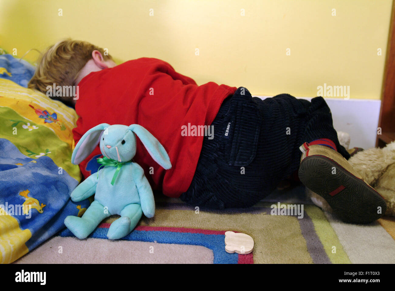 Enfant endormi dans une classe maternelle avec un jouet lapin bleu Banque D'Images