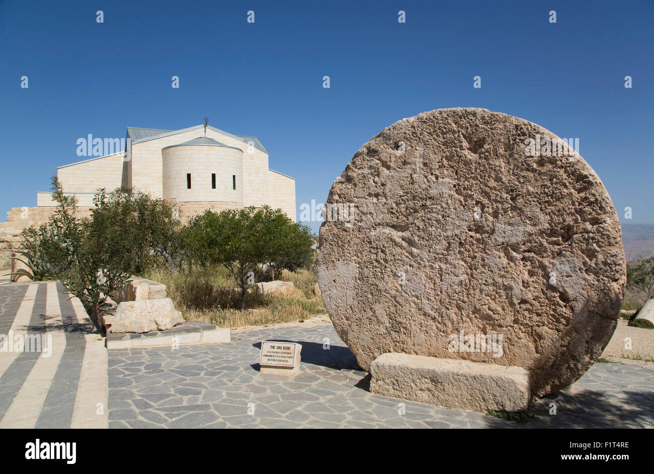 Abu Badd, un rolling stone utilisée pour fortifier une porte, Moïse Memorial Church à l'arrière-plan, le Mont Nebo, Jordanie, Moyen-Orient Banque D'Images