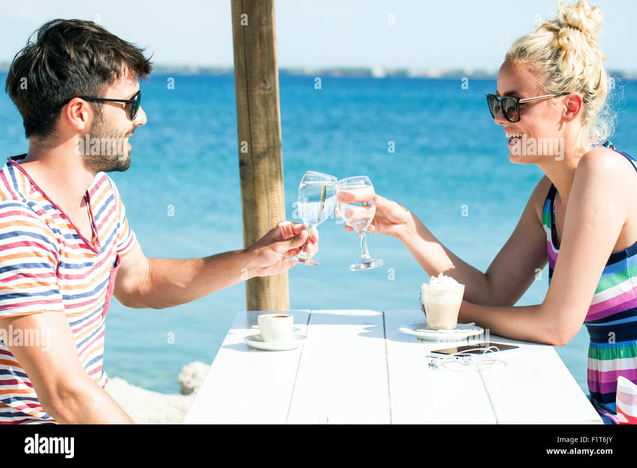Young couple sitting at table in beach bar Banque D'Images
