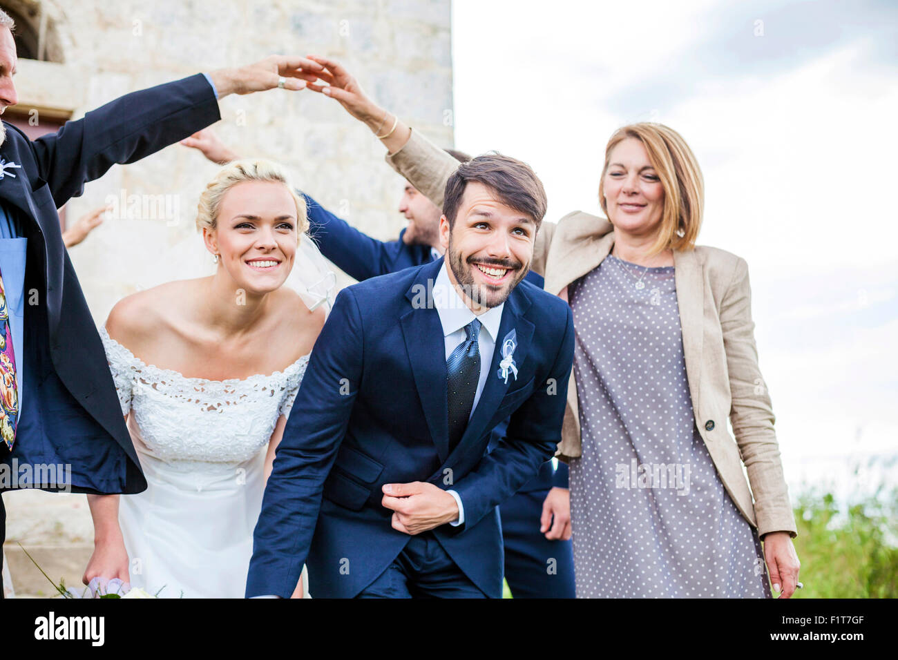 Couple de jeunes mariés quitte chapelle entourée d'invités du mariage Banque D'Images