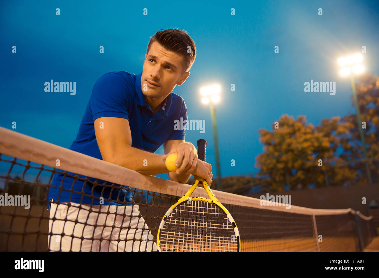 Portrait d'un beau joueur de tennis masculin debout dans la cour et à l'écart Banque D'Images