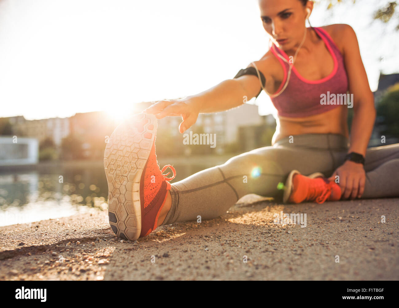 Jeune femme runner stretching jambes avant de faire son entraînement d'été. La sportive de préchauffage avant d'entraînement en plein air. Banque D'Images