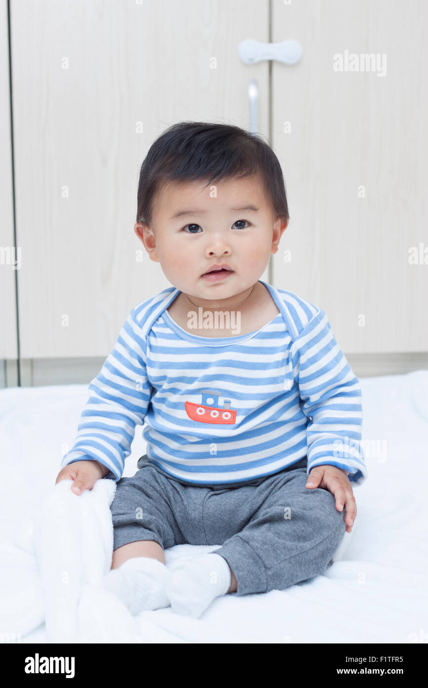 Cute baby boy sitting chinois sur une couverture blanche Banque D'Images
