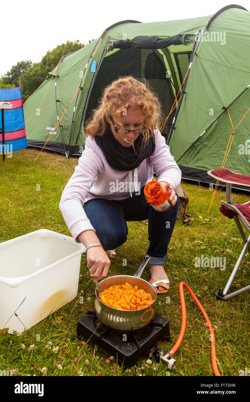 Femme la cuisson des pâtes sur un réchaud de camping. Karrageen Camping, Hope Cove, Devon, Angleterre, Royaume-Uni. Banque D'Images