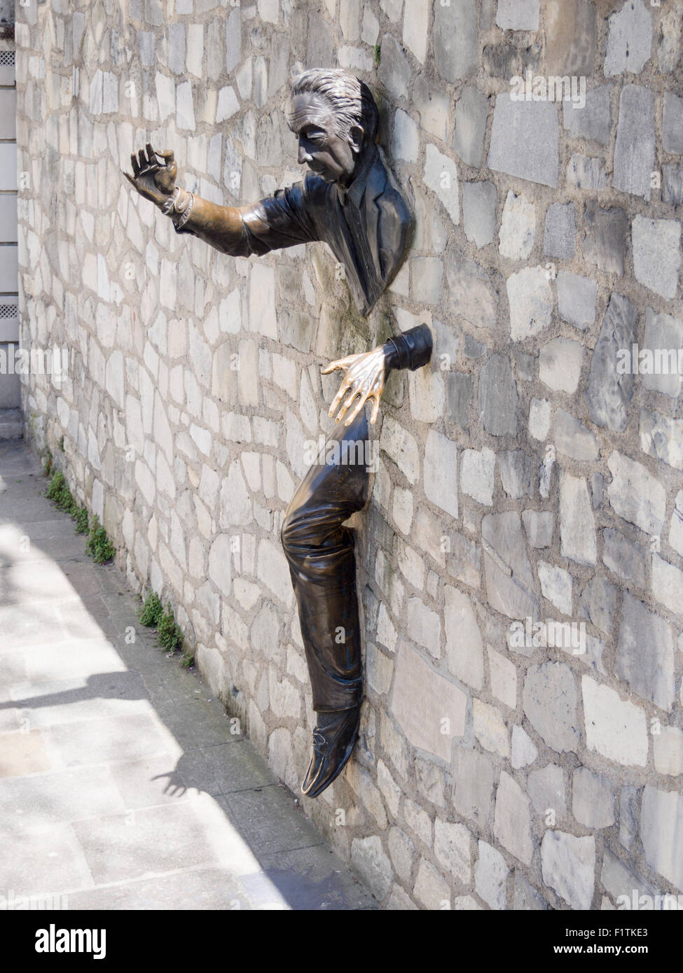 Walker à travers les murs : Le Passe-Muraille. Sculpture d'un homme marchant à travers un mur de pierre à Montmartre Banque D'Images