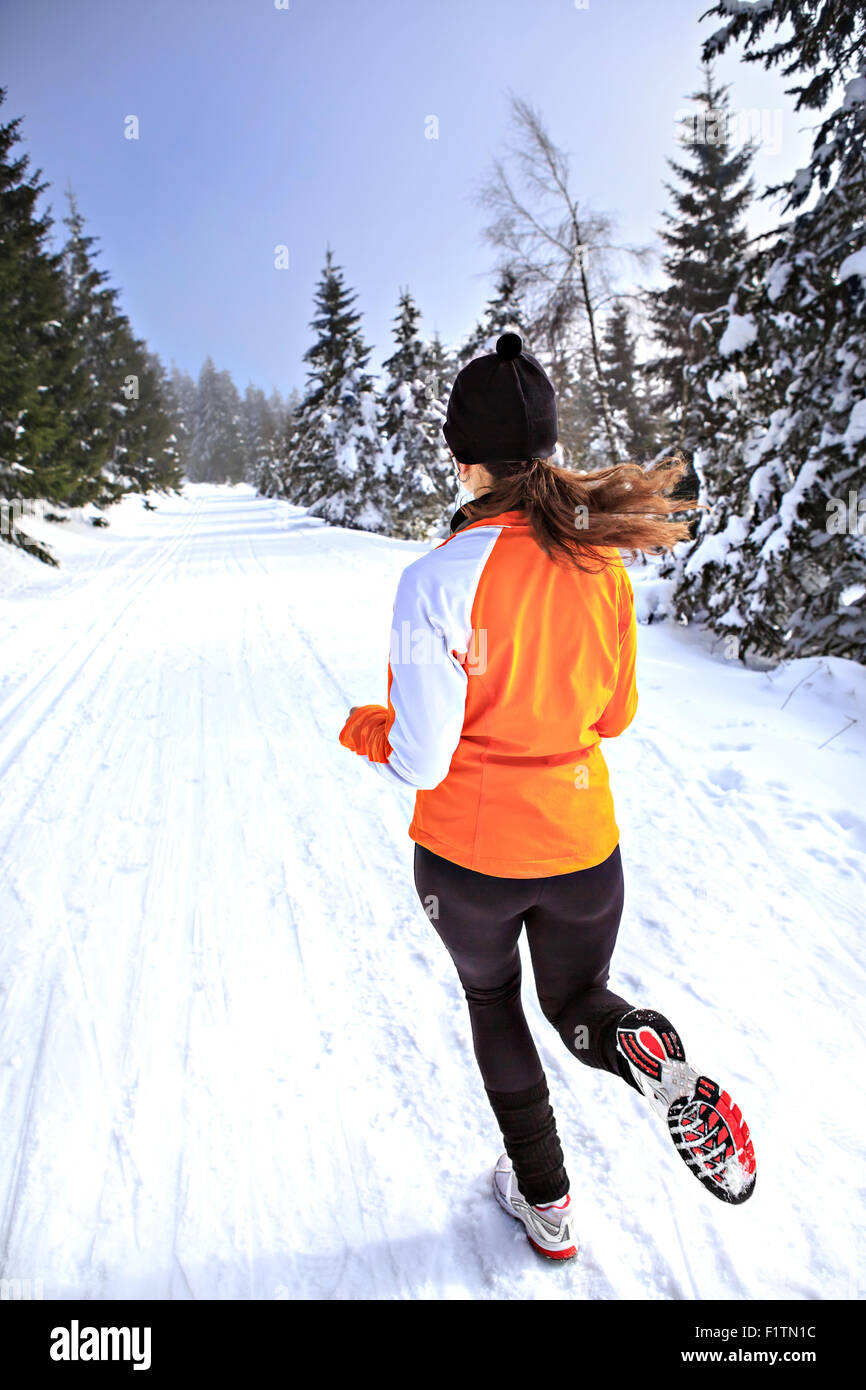 Une jeune femme le jogging dans la forêt d'hiver Banque D'Images