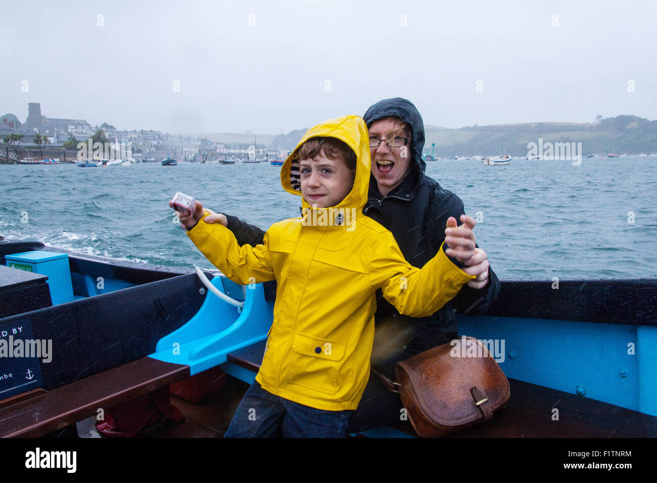 Mère et fils (6 ans) sous la pluie sur le ferry pour passagers Salcombe entre la plage de East Portlemouth et Salcombe,Devon, Angleterre, Royaume-Uni. Banque D'Images