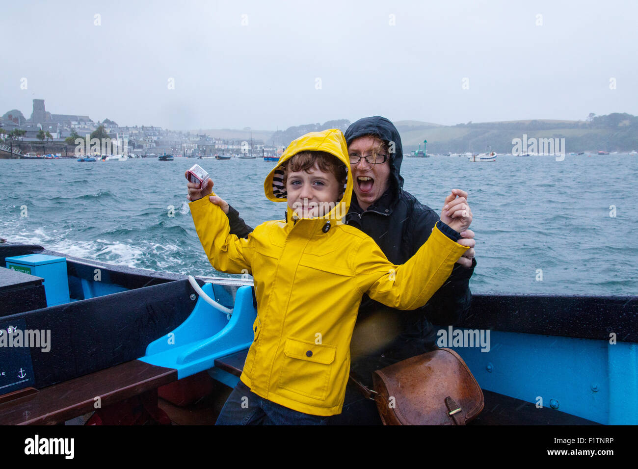 Mère et fils (6 ans) sous la pluie sur le ferry pour passagers Salcombe entre la plage de East Portlemouth et Salcombe,Devon, Angleterre, Royaume-Uni. Banque D'Images