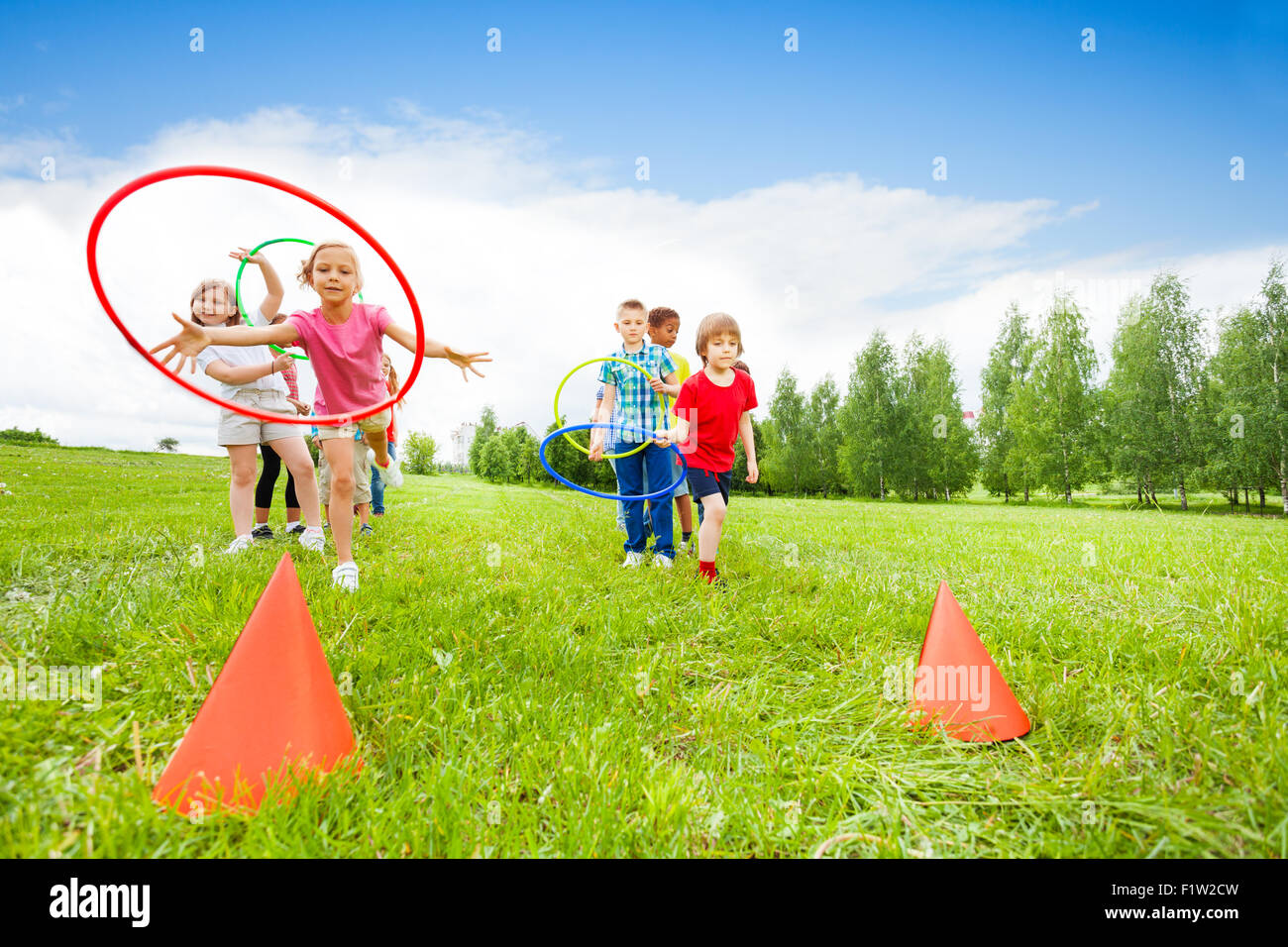 Jeter les enfants espiègles sur les cônes colorés hoops Banque D'Images
