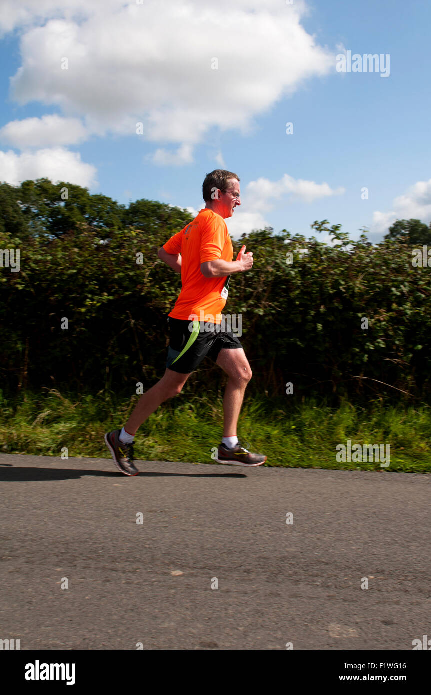 Demi-marathon runner sur une route de campagne, dans le Warwickshire, Royaume-Uni Banque D'Images