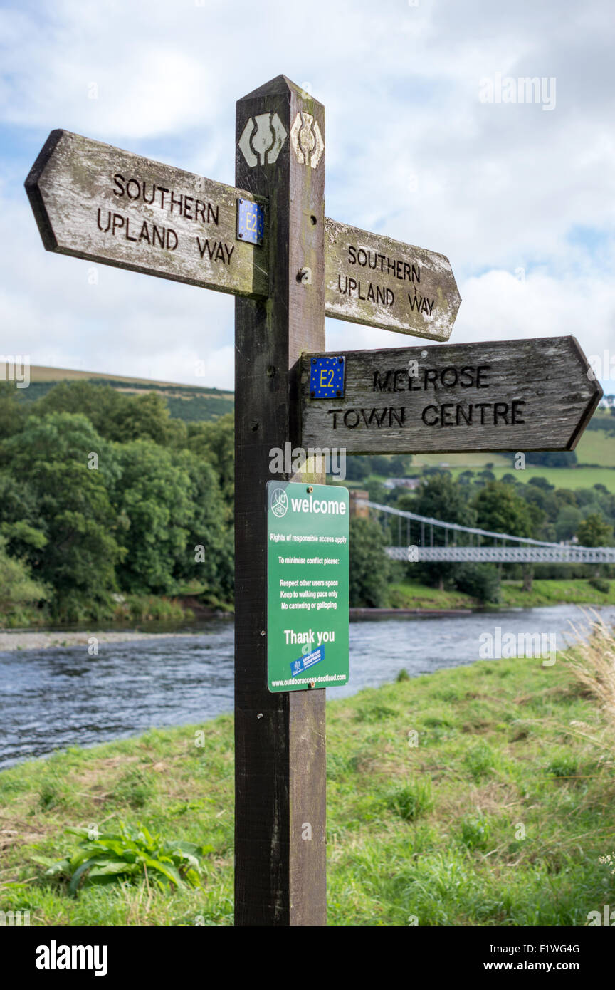 Le sud de l'Upland Way marcheurs signpost with Chainbridge en arrière-plan. Sur la rivière Tweed à Melrose, Scottish Borders, R.-U. Banque D'Images