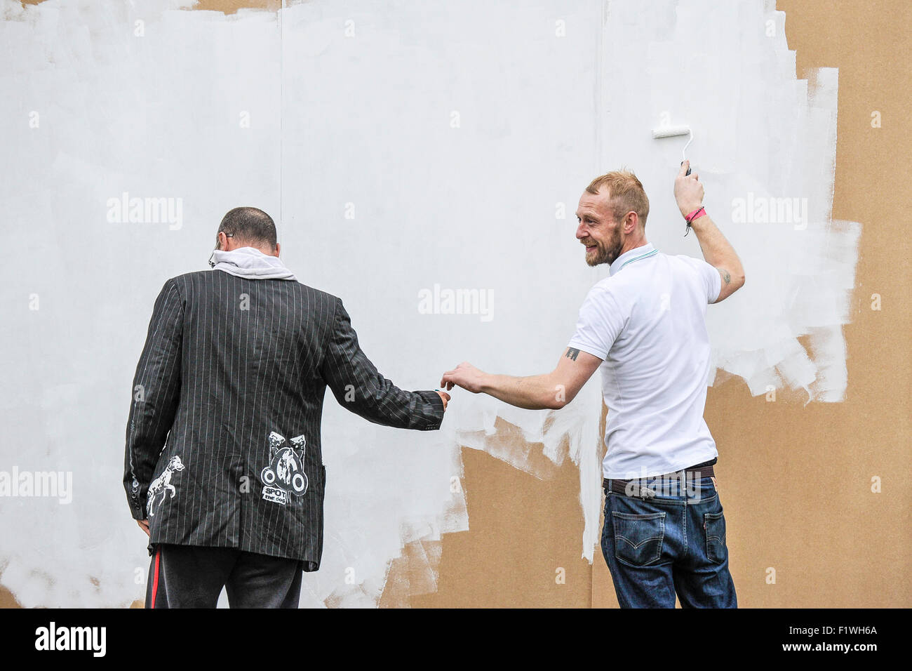 Un homme à l'aide d'un rouleau pour peindre un mur en bois. Banque D'Images