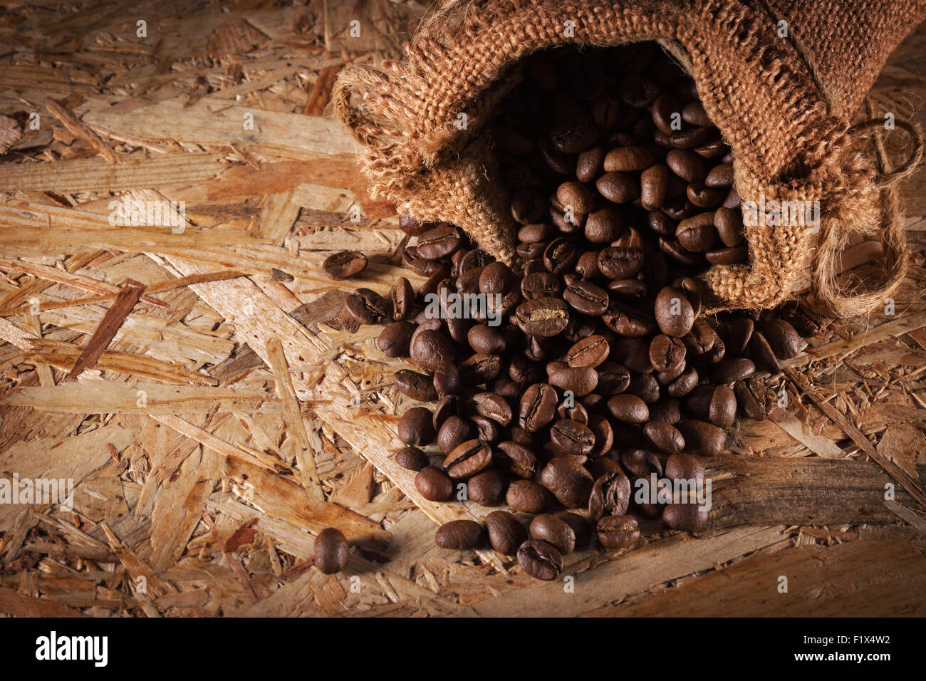 Sac avec café en grains isolés sur le fond en bois. Banque D'Images