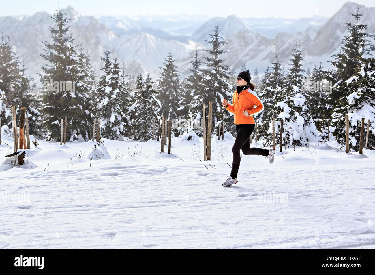 Une jeune femme le jogging dans la forêt d'hiver Banque D'Images
