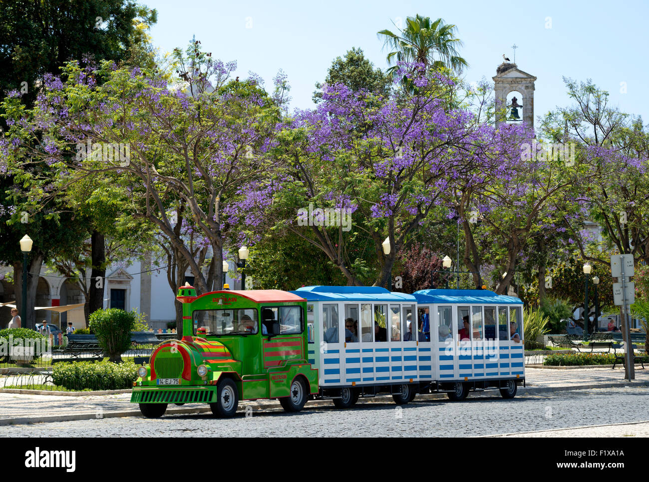 'Train touristique' sur la place centrale, Faro, Algarve, avec jacarandas en fleurs Banque D'Images