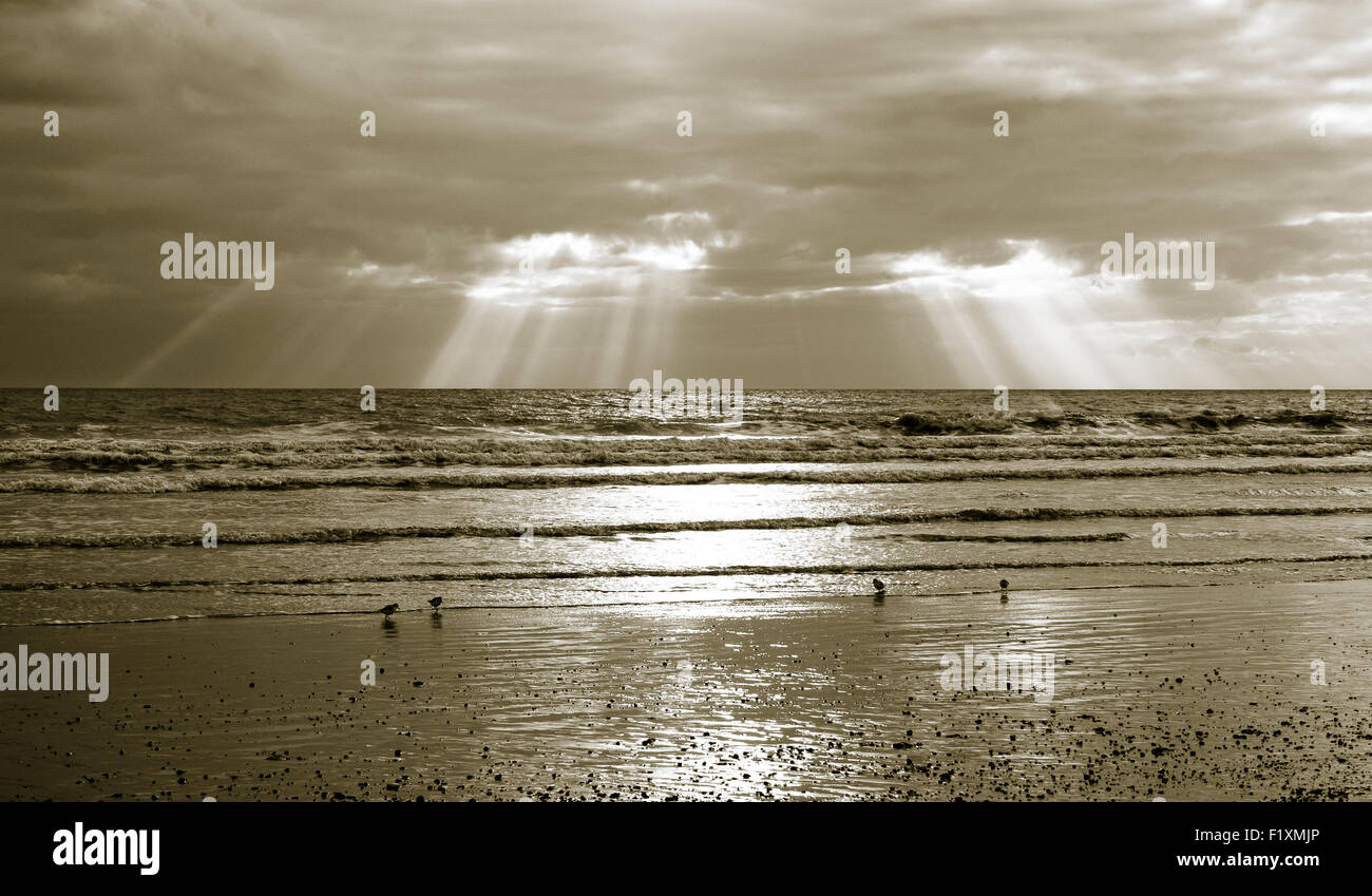 Split shot tonique de rayons crépusculaires sur la Manche à West Beach, Littlehampton comme la marée se retire. Banque D'Images