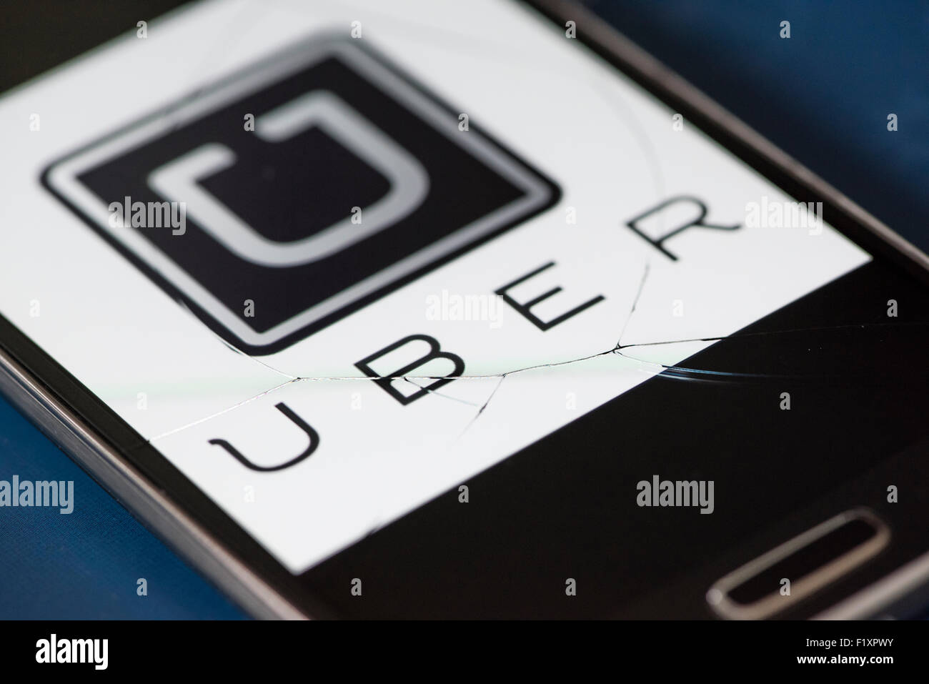 L'icône de l'application de service de taxi Uber est affiché sur un smartphone à l'origine d'une grande fissure dans le verre de l'écran tactile. Banque D'Images