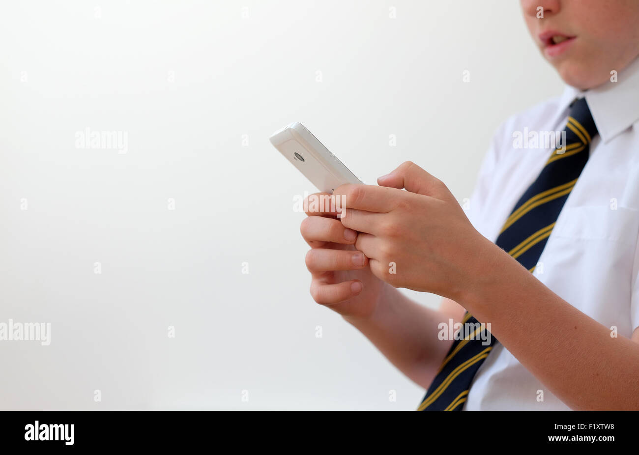 Un écolier en uniforme en utilisant son téléphone mobile ( texto ) UK Banque D'Images