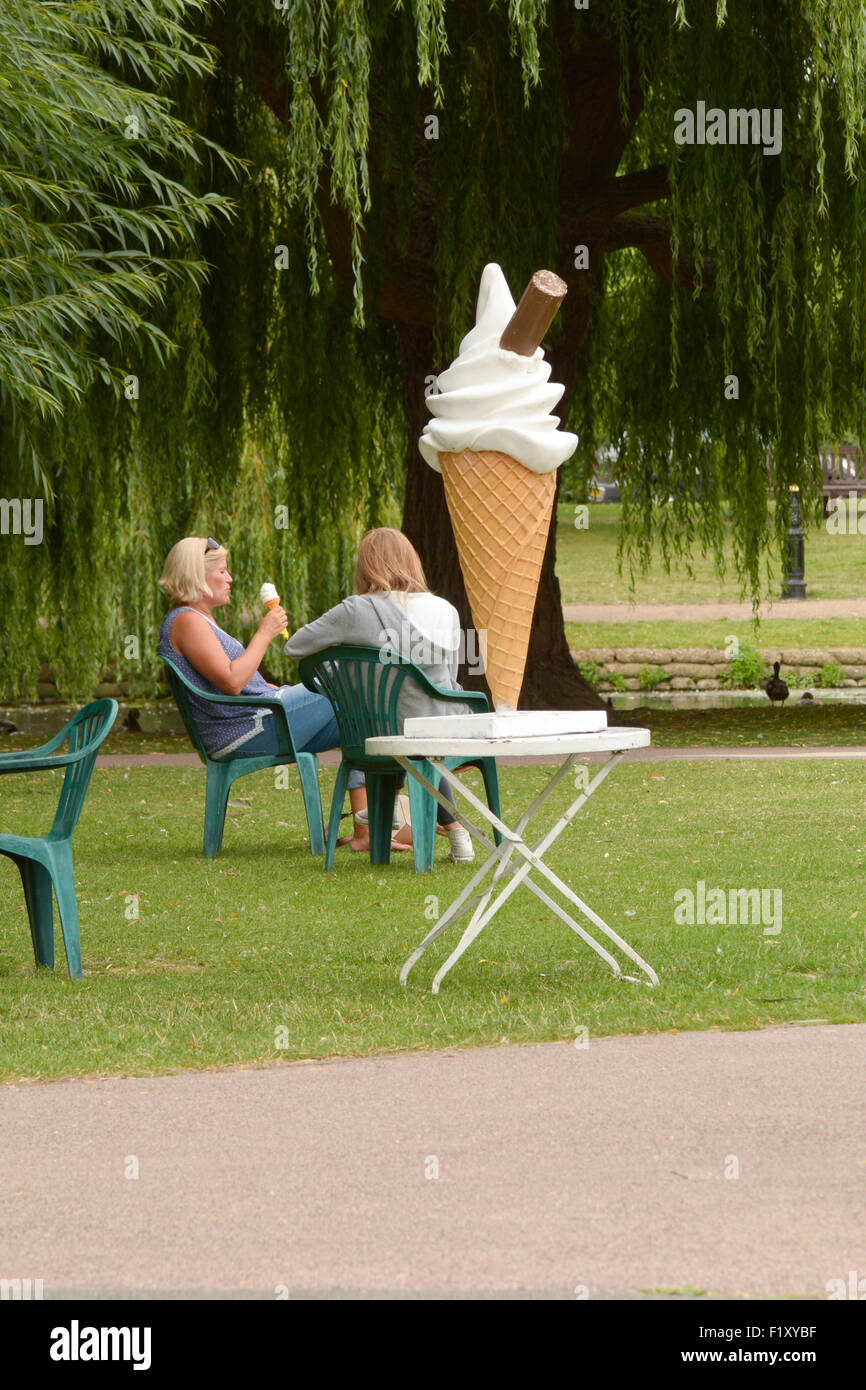 La crème glacée 'envy' deux femmes de manger un cornet de crème glacée à la terrasse d'un café à côté d'un grand modèle de la crème glacée à Bedford, Bedfordshire, Angleterre Banque D'Images