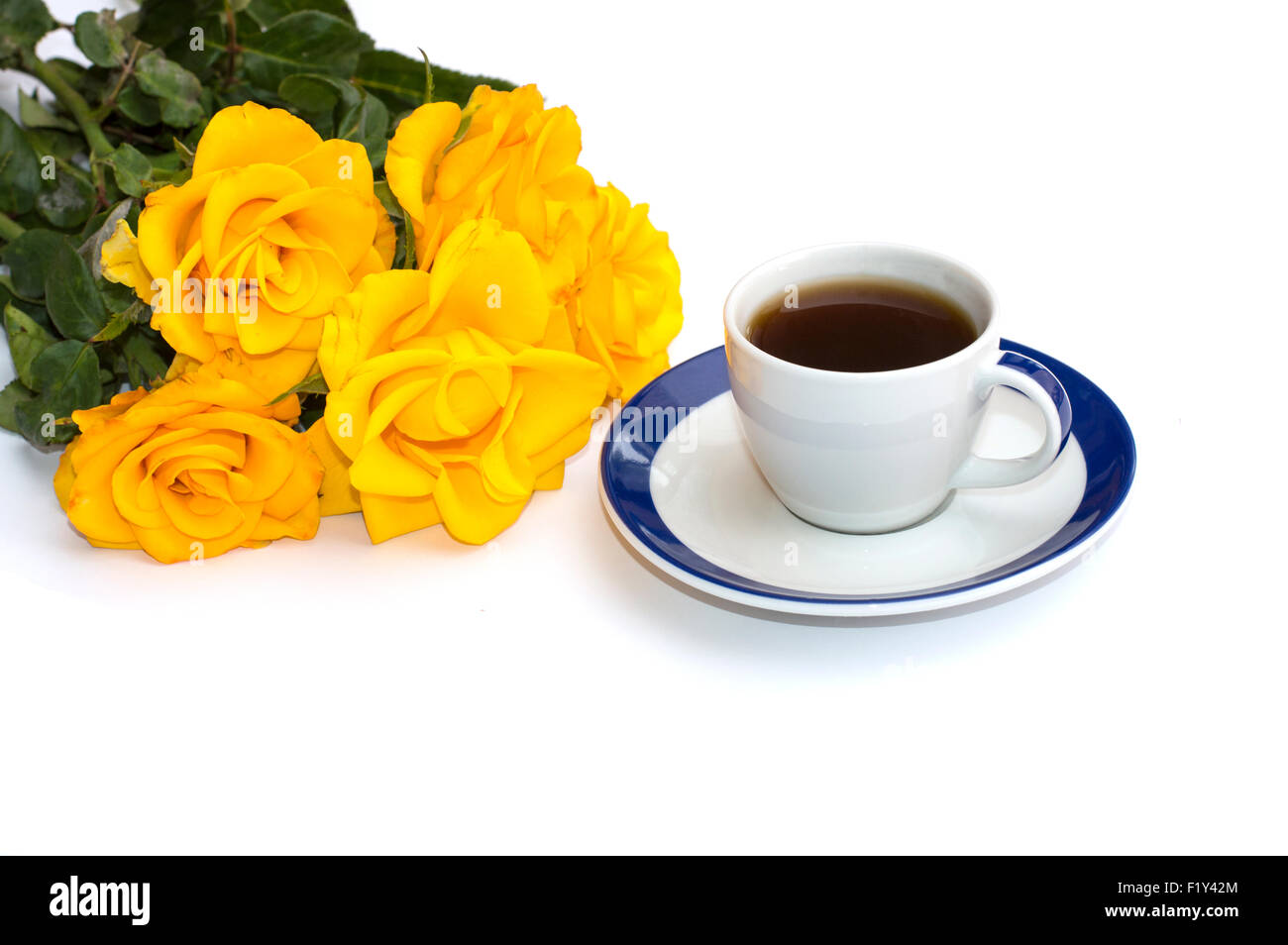 Tasse de café sur une soucoupe blanc et un bouquet de roses jaunes Banque D'Images