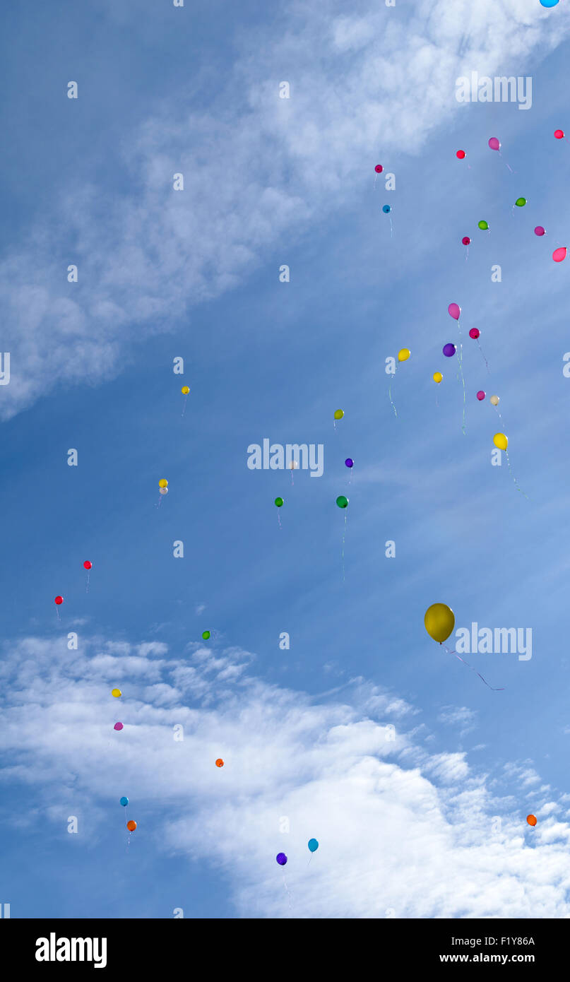 Nombreuses couleurs ballons volent (hover) dans le ciel bleu avec des nuages Banque D'Images