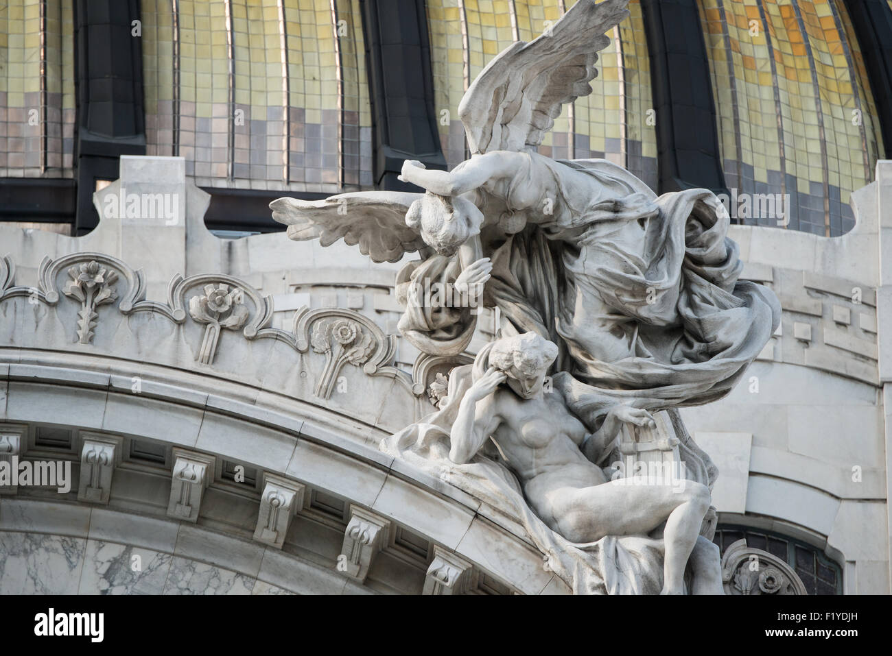 Palacio de Bellas Artes figures sculpturales Mexico // MEXICO CITY, MEXICO — des figures sculpturales ornées représentant la musique et les arts ornent le fronton au-dessus de l'entrée principale du Palacio de Bellas Artes. Le palais, achevé en 1934, est le premier opéra et centre culturel du Mexique, accueillant des représentations de l'Orchestre symphonique national et du Ballet Folklórico de México. La façade du bâtiment combine les styles architecturaux néoclassique et Art Nouveau, avec du marbre italien de Carrare habillé l'extérieur. Ces sculptures décoratives illustrent l'ornement architectural détaillé Banque D'Images