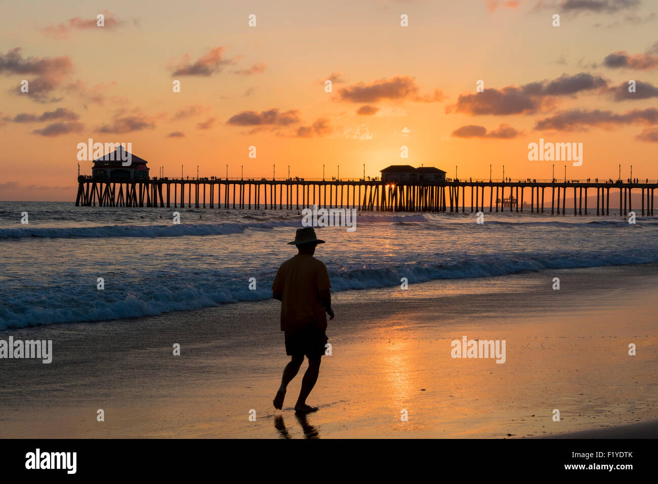 Un homme le jogging sur la plage de Huntington Beach Pier Californie silhouette sur le coucher du soleil en été Banque D'Images