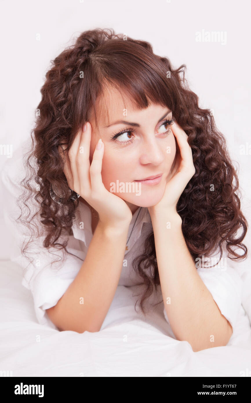 Belle jeune femme en chemise blanche sur un lit Banque D'Images