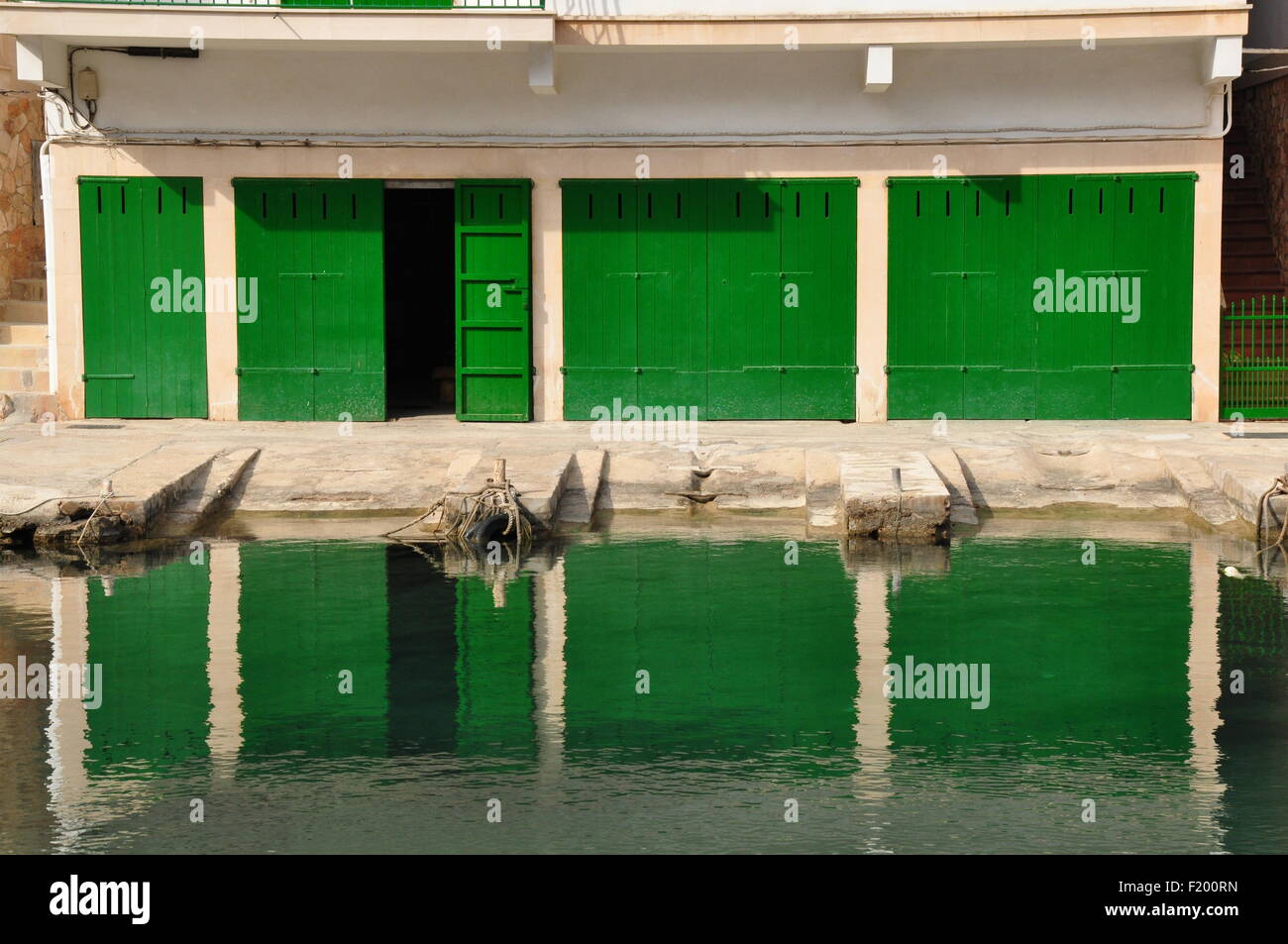 Les portes d'un hangar à bateaux vert reflète dans une mer calme Banque D'Images