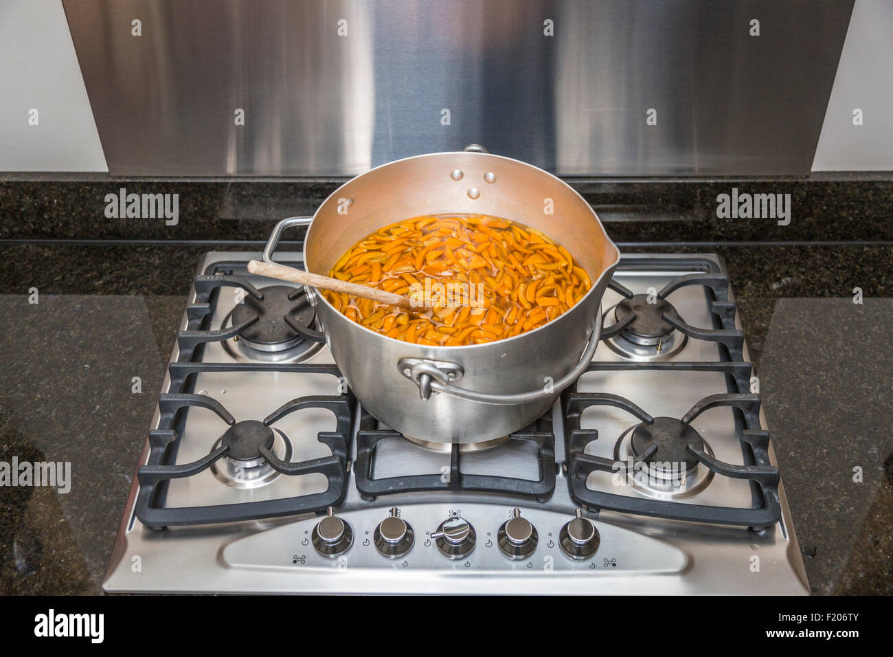 Panneaux oranges pelées dans un métal chauffage préservant le moule sur une cuisinière à gaz en préparation à ébullition pour faire de la marmelade faite maison Banque D'Images