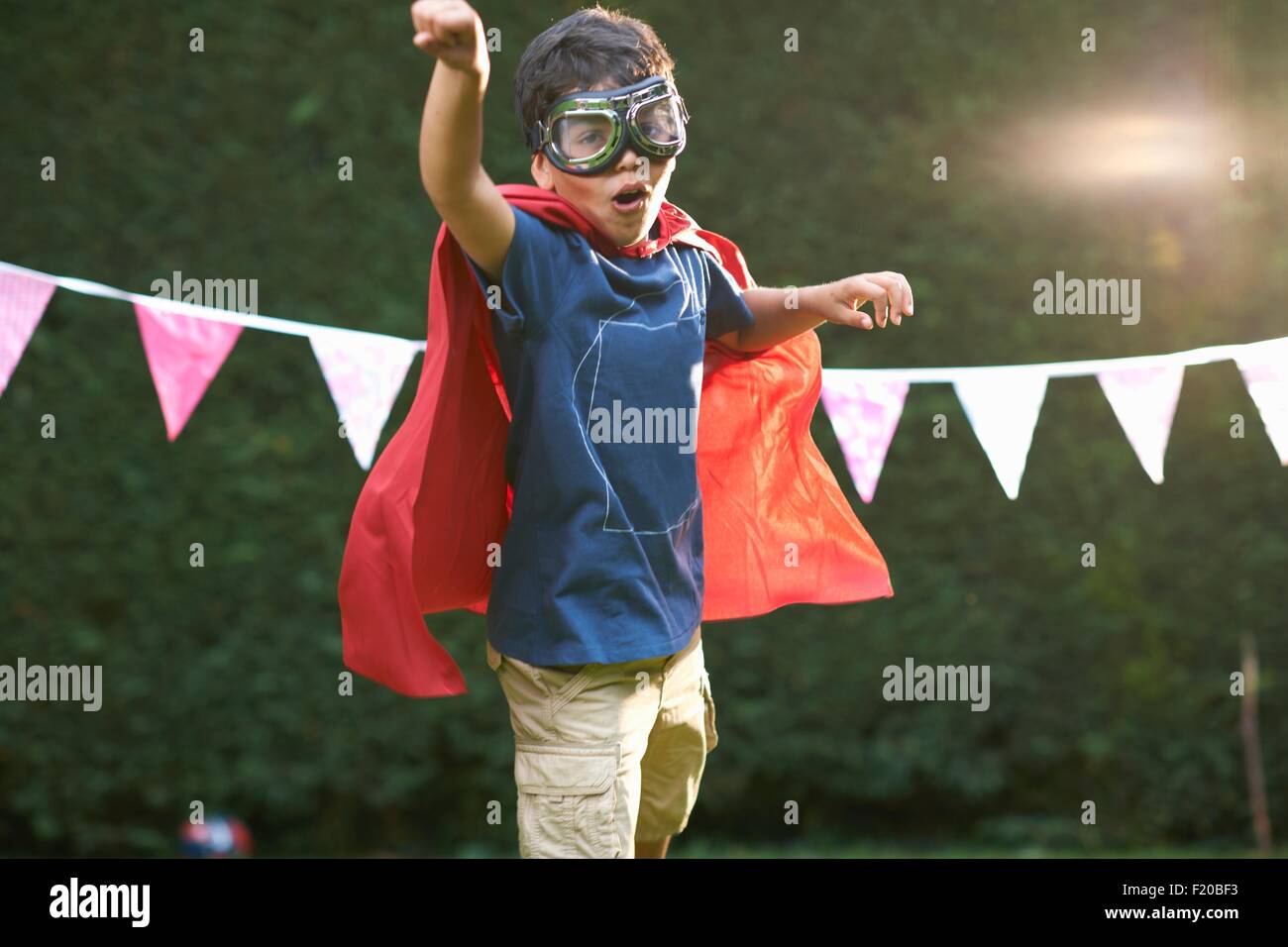 Garçon portant ces lunettes et cape en position de super-héros Banque D'Images