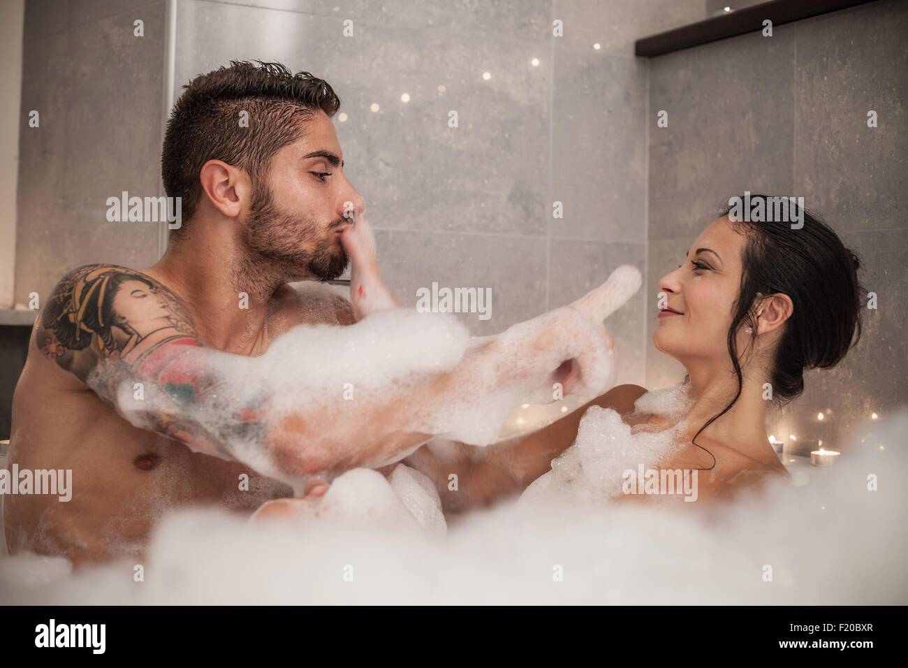 Jeune couple jouant avec des bulles dans le bain de mousse Banque D'Images