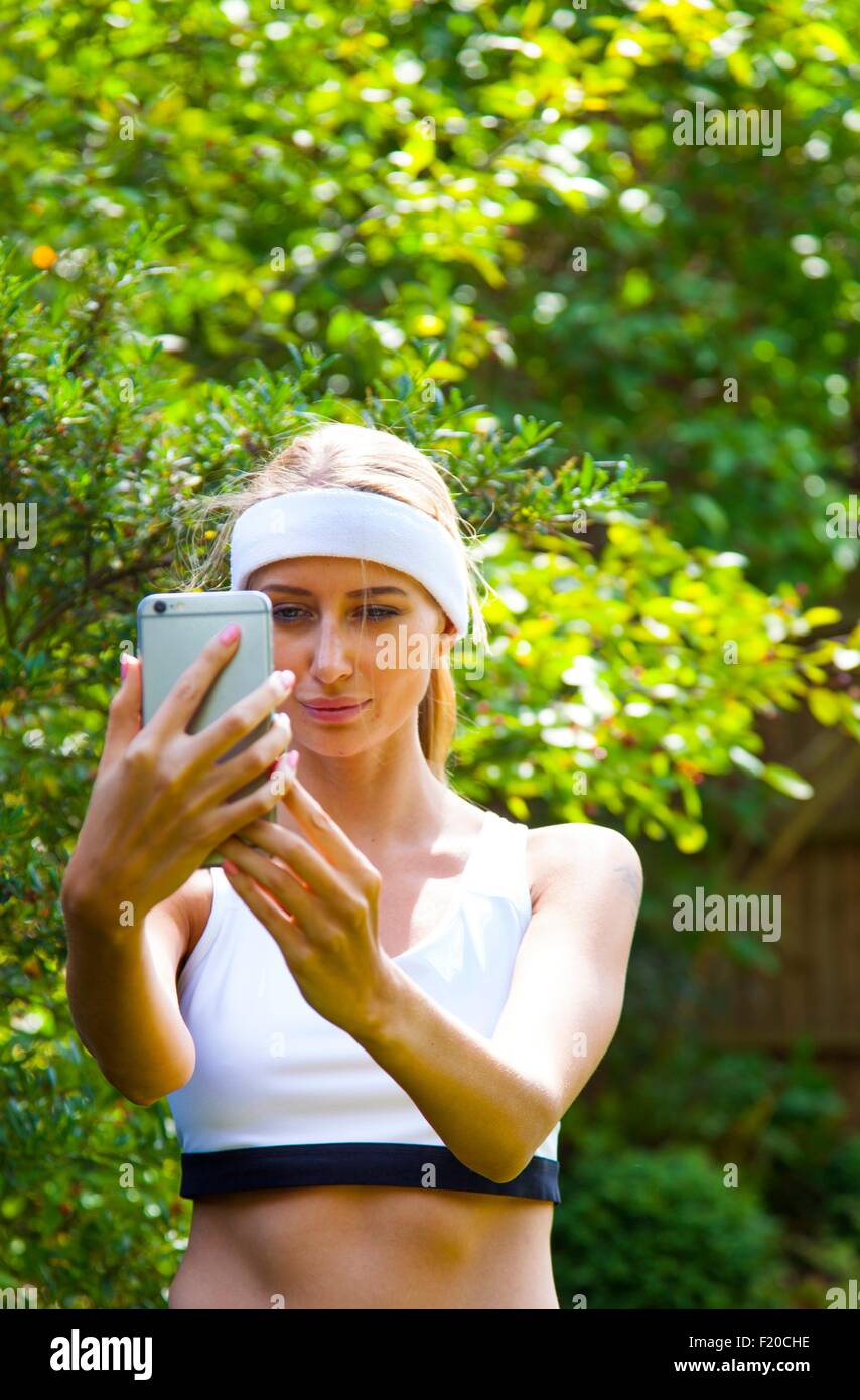 Woman wearing sports top prenant en selfies jardin Banque D'Images