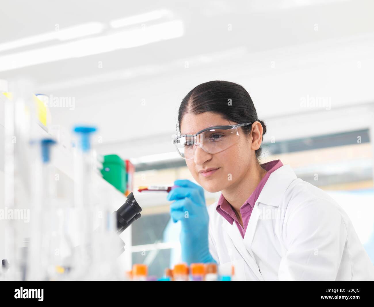 Jeune femme scientifique affichage tube de sang au cours de l'essai clinique d'échantillons médicaux dans un laboratoire Banque D'Images