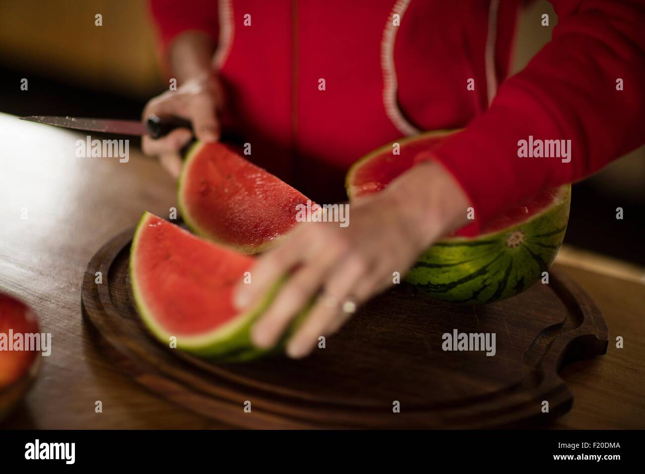 Portrait of mature woman slicing watermelon in kitchen Banque D'Images
