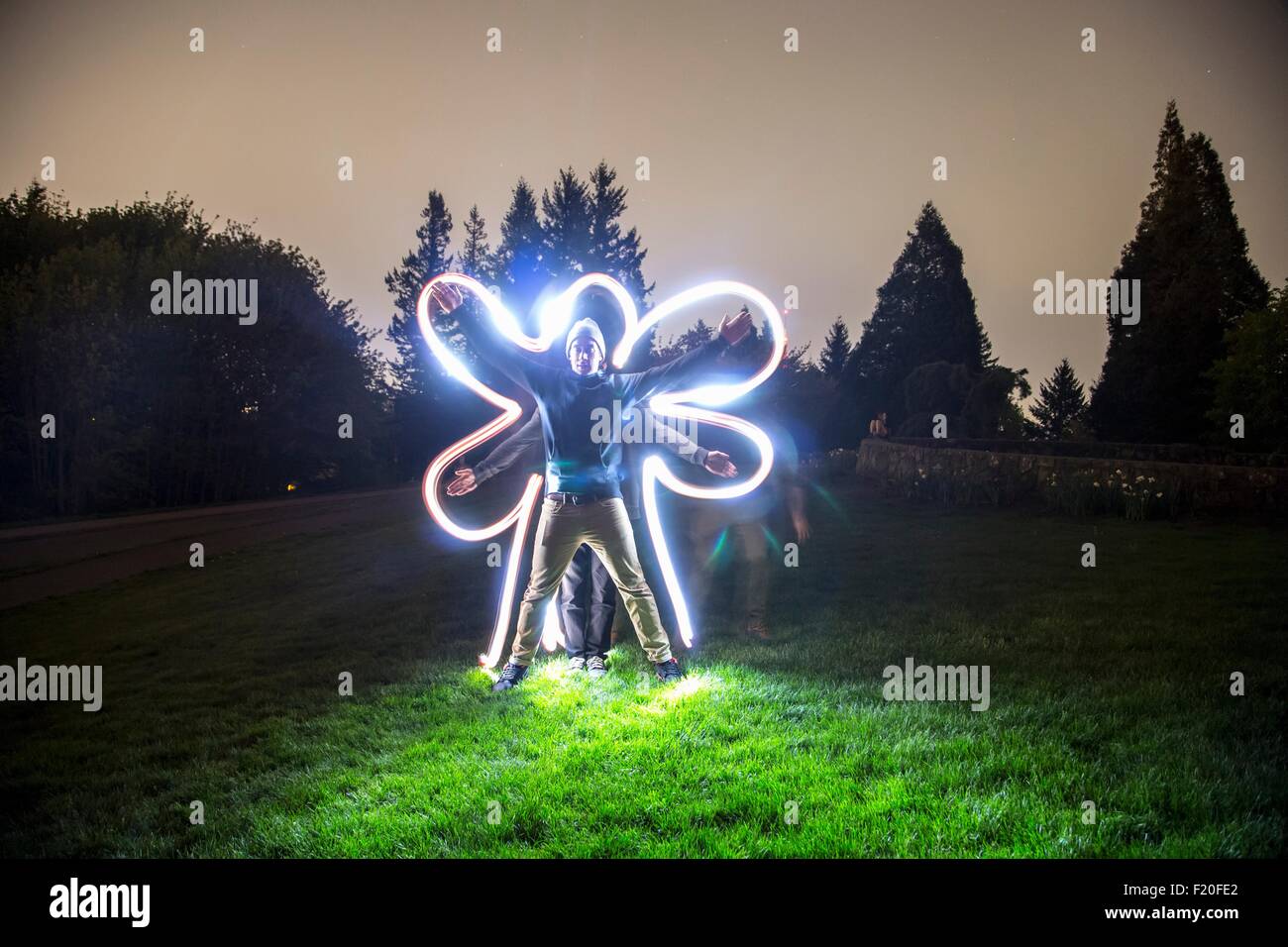 Deux hommes debout ensemble dans le champ à la tombée du jour, la création d'étoile avec des organes, ami retraçant la forme du corps avec la lumière trail Banque D'Images
