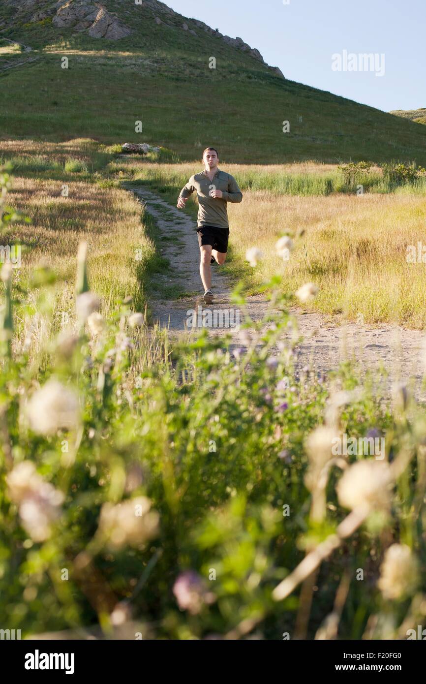 Young male runner fonctionnant en bas colline track Banque D'Images