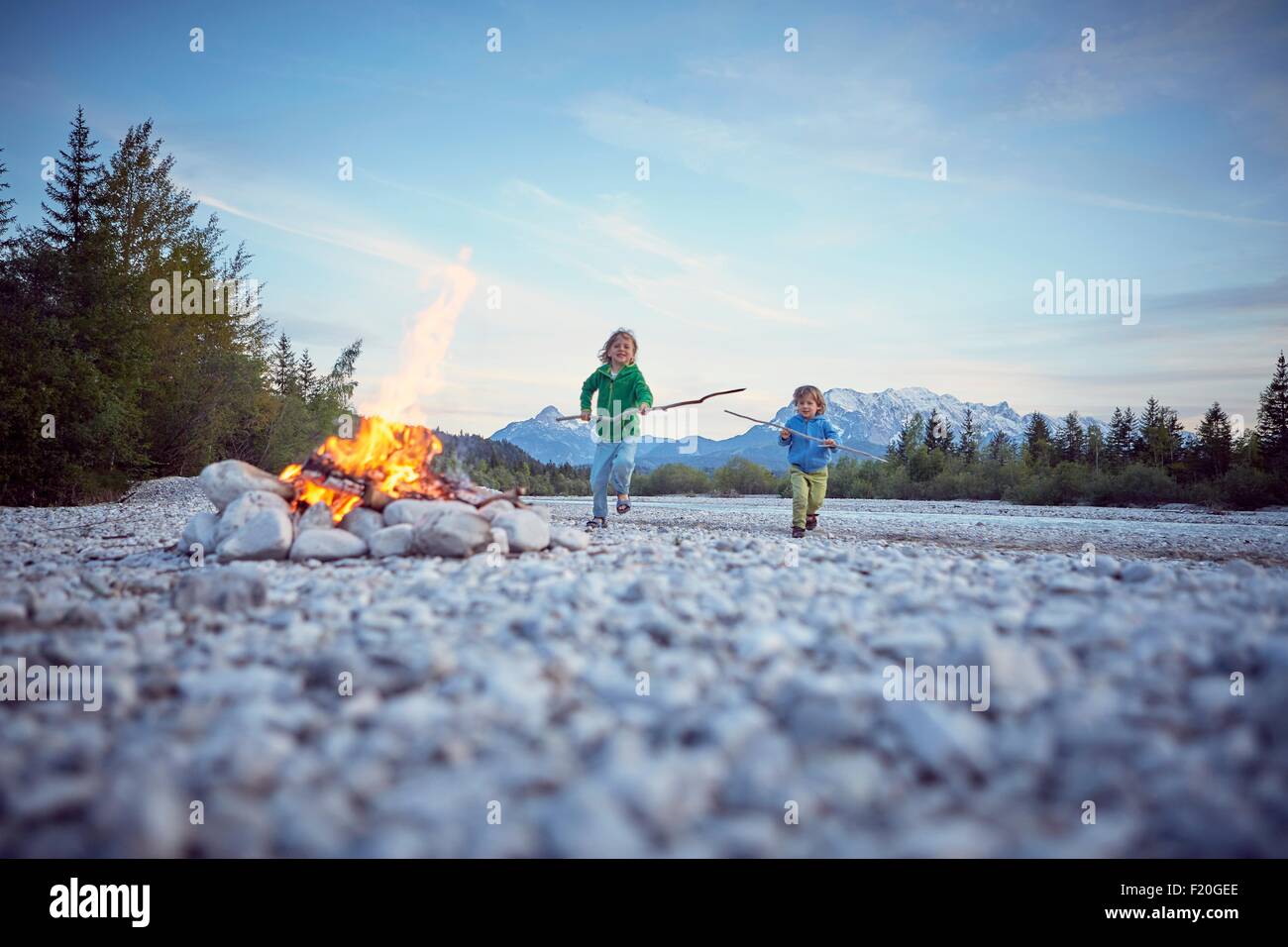 Vue avant d'enfants courant à campfire holding sticks, Wallgau, Bavière, Allemagne Banque D'Images