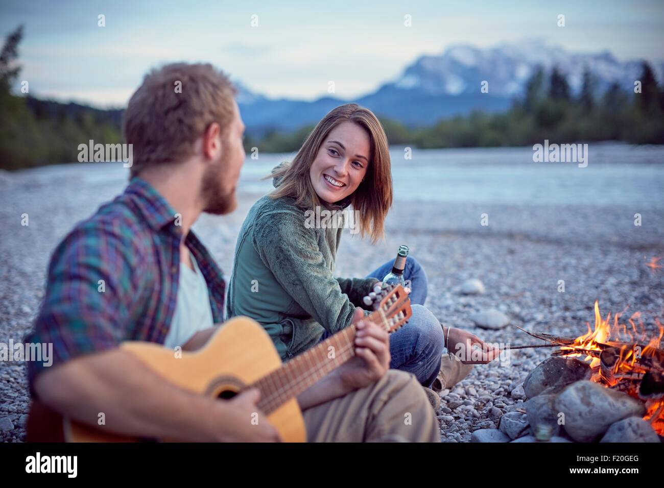 Jeune couple assis par camp à jouer de la guitare, Wallgau, Bavière, Allemagne Banque D'Images