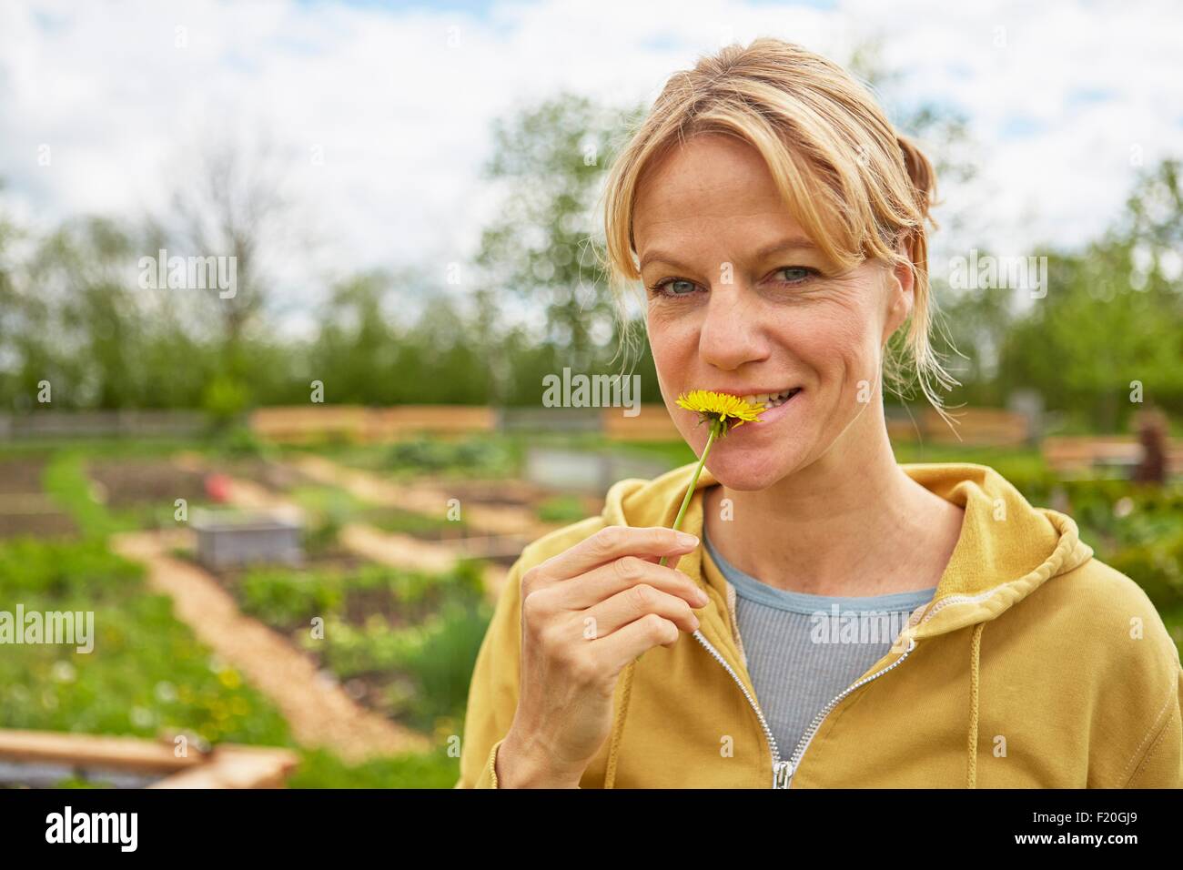 Portrait of young woman outdoors, jardinage, fleur de dégustation Banque D'Images