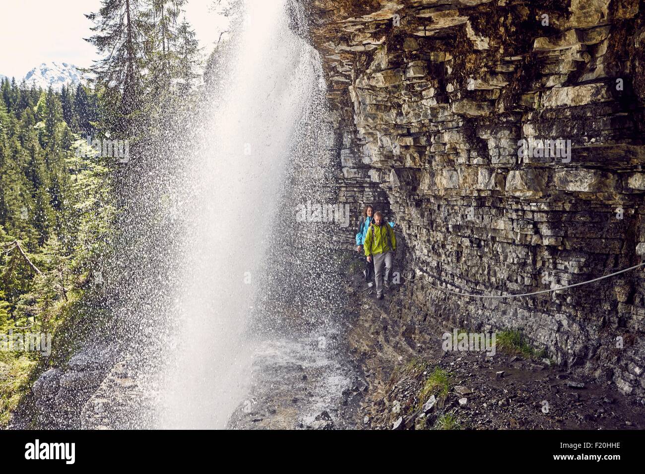 Jeune couple en train de marcher sous une cascade, Tyrol, Autriche Banque D'Images