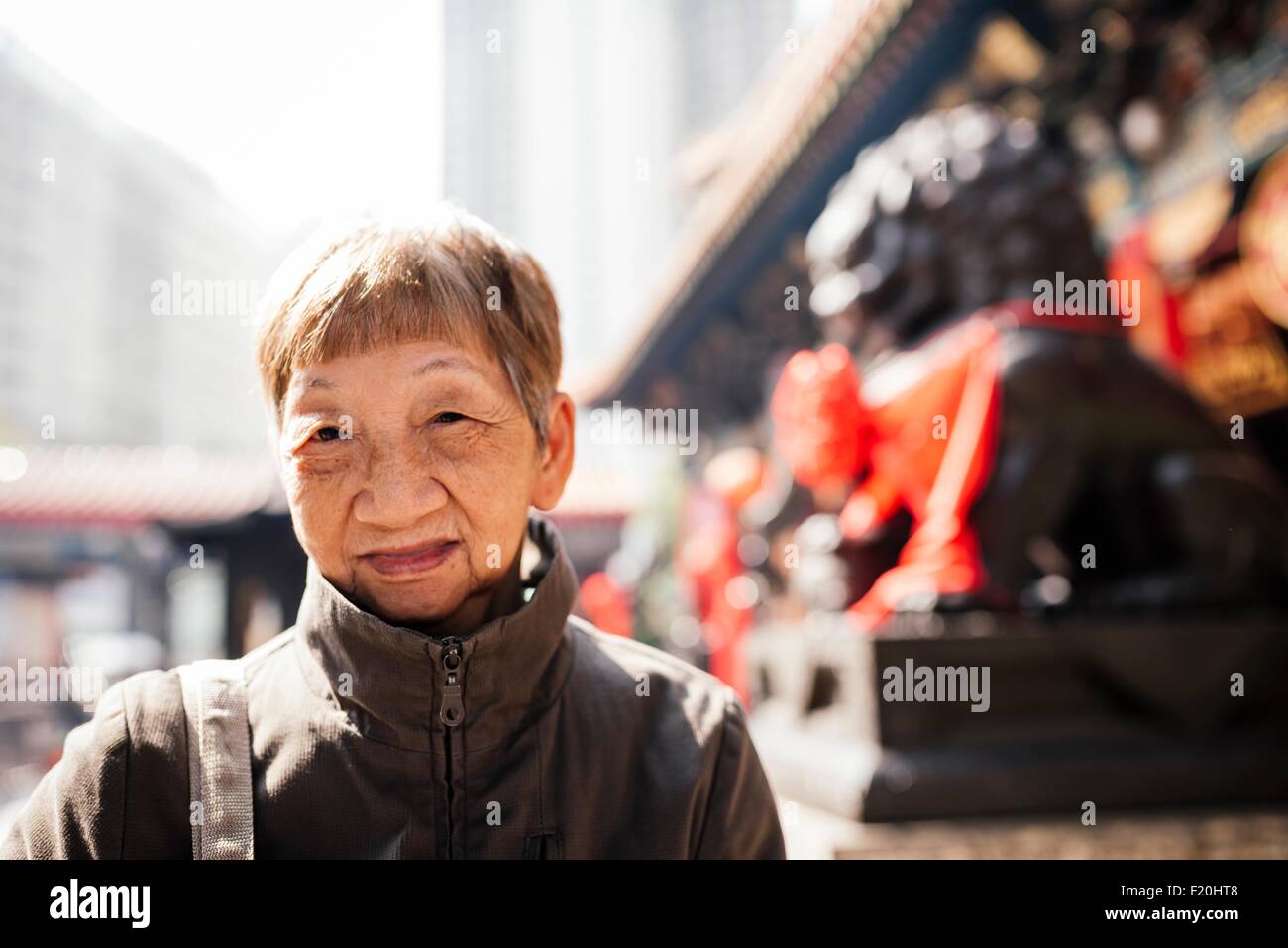 Portrait of senior woman wearing manteau en face de lion statue, looking at camera Banque D'Images