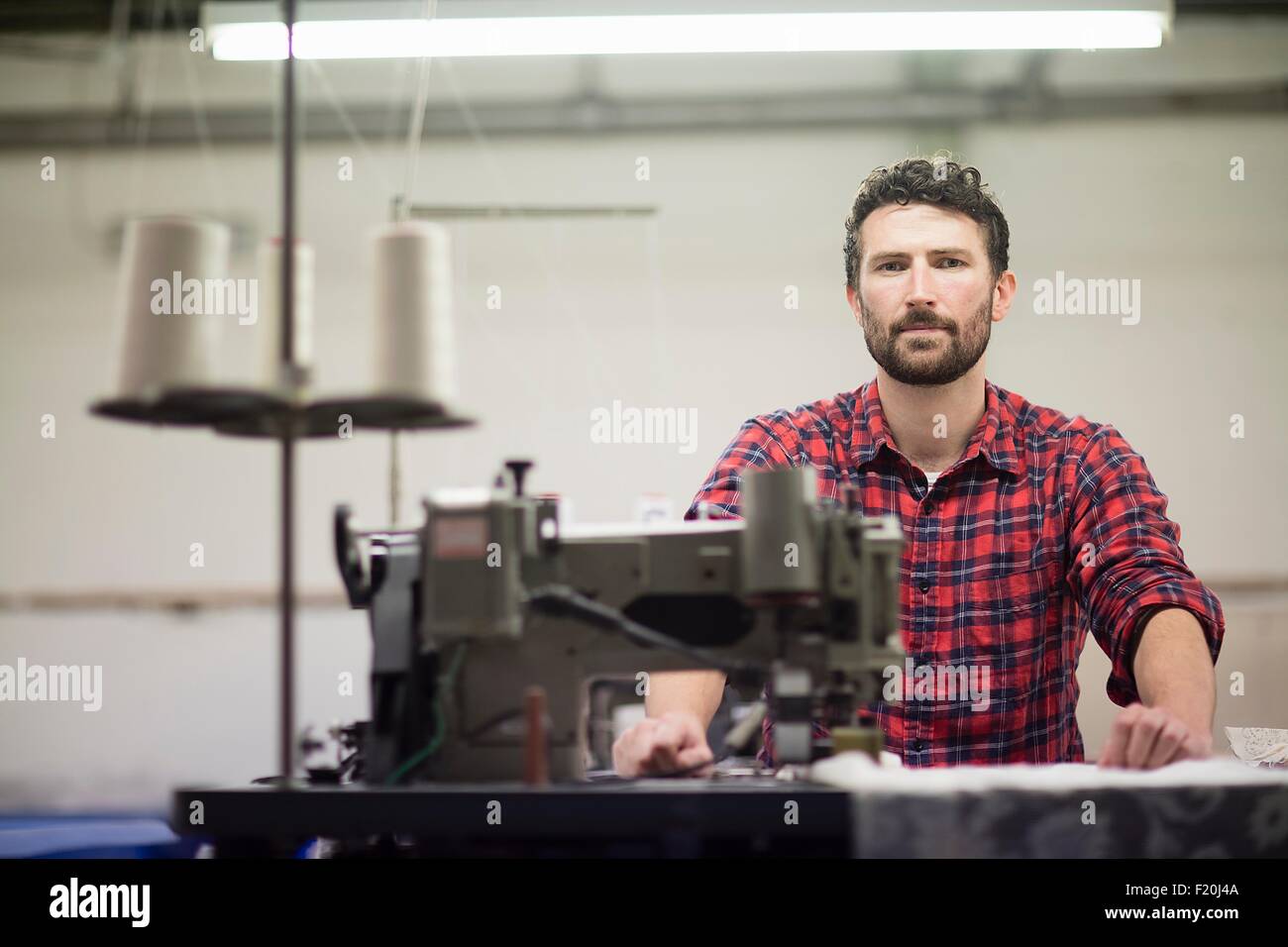 Portrait of male designer textile à l'aide de machine à coudre dans ancienne usine textile Banque D'Images