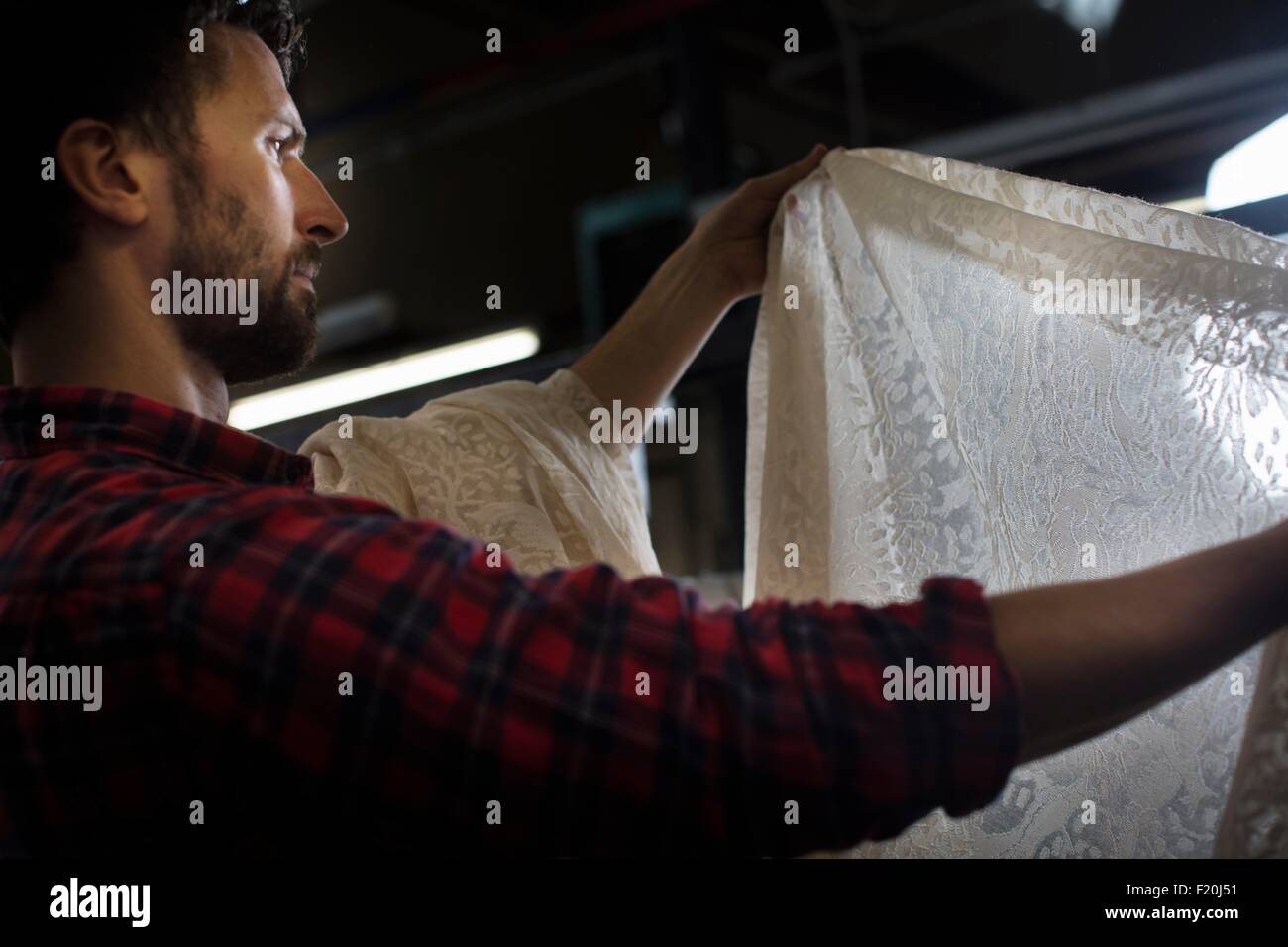 Portrait of male weaver l'examen de l'ancien produit de la dentelle machine à tisser dans l'usine de textile Banque D'Images