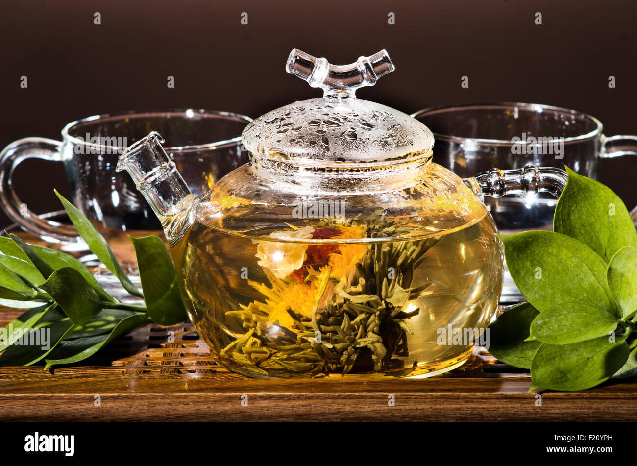 Photo horizontale de la théière en verre avec du thé vert dans la tasse, sur le backgrpund brun, gros plan Banque D'Images